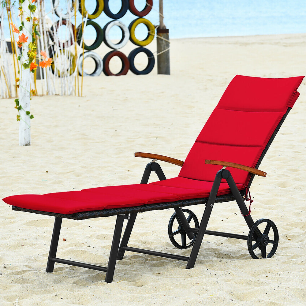 Red folding patio rattan lounge chair with wheels, adjustable backrest, ideal for beach and poolside relaxation.