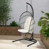 Hanging wicker egg chair with stand in beige, featuring a sturdy steel frame and comfortable cushions for outdoor.