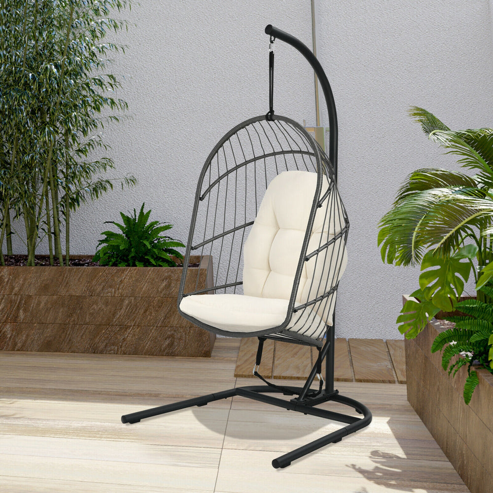 Hanging wicker egg chair with stand in beige, featuring a sturdy steel frame and comfortable cushions for outdoor.