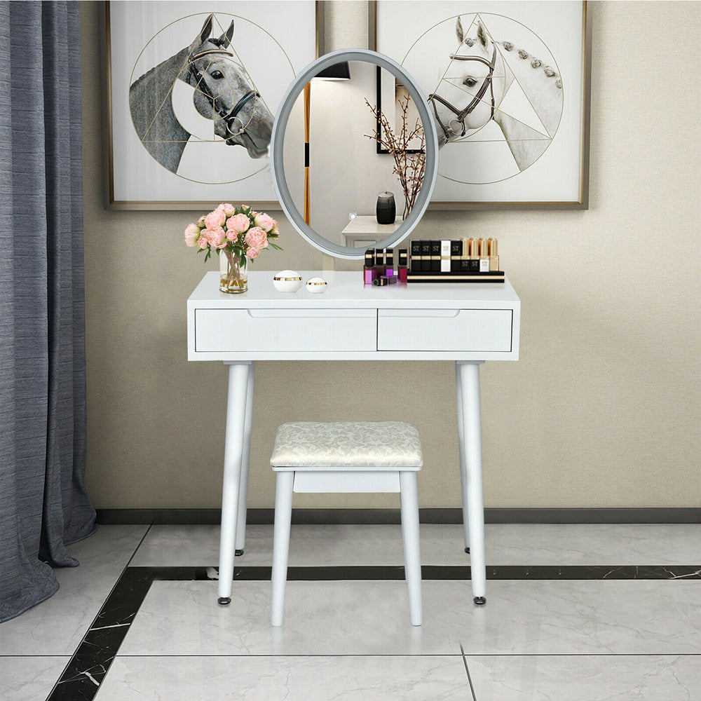 Elliptical lighted mirror on a white vanity table with two drawers and a cushioned stool for comfortable makeup.