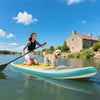 Inflatable 11 feet stand up paddle board with a non-slip deck, paddler, and dog on a calm lake for outdoor fun.