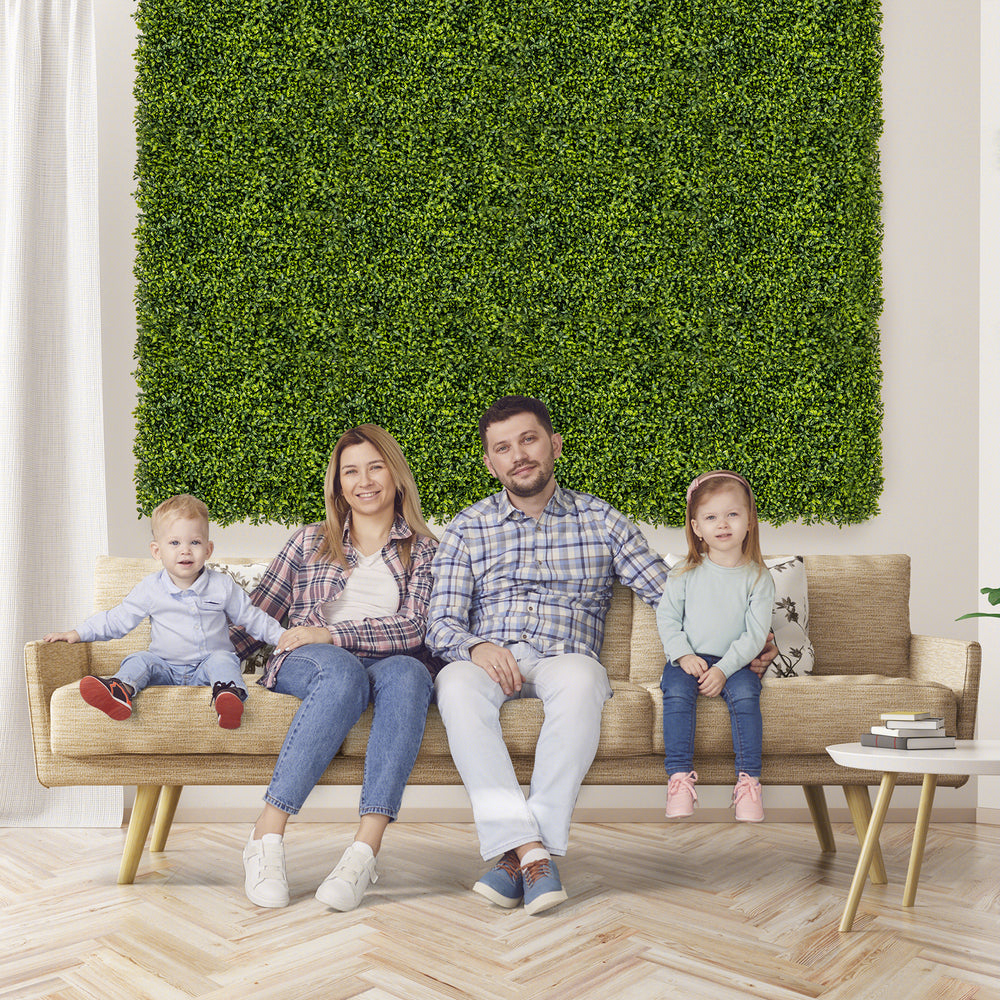 Artificial hedge boxwood panels in a living room setting, ideal for creating privacy screens or green wall backdrops.