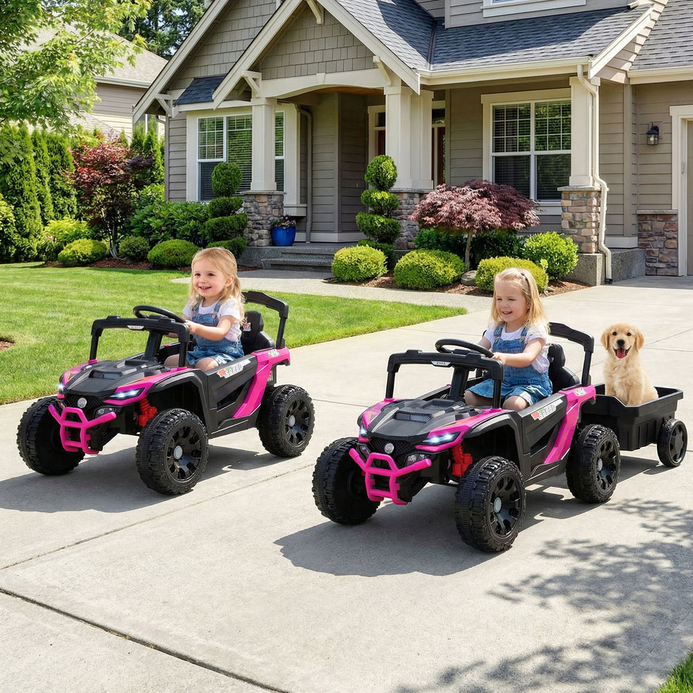 Two kids driving a pink and black 12V battery-powered ride-on tractor with a detachable trailer for outdoor fun.