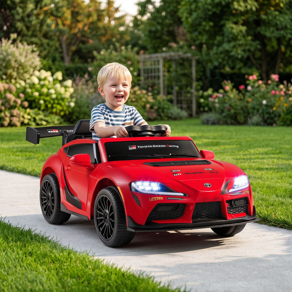 Red 12V kids electric car with licensed Toyota styling, shown with a child at the wheel outdoors.