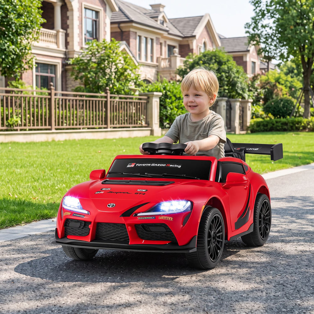 Child driving a red 12V kids electric car with parent remote control, shown from the front on a driveway.