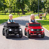 Two kids enjoy driving licensed Mercedes Benz EQG 580 ride-on cars in red and black on a park pathway.