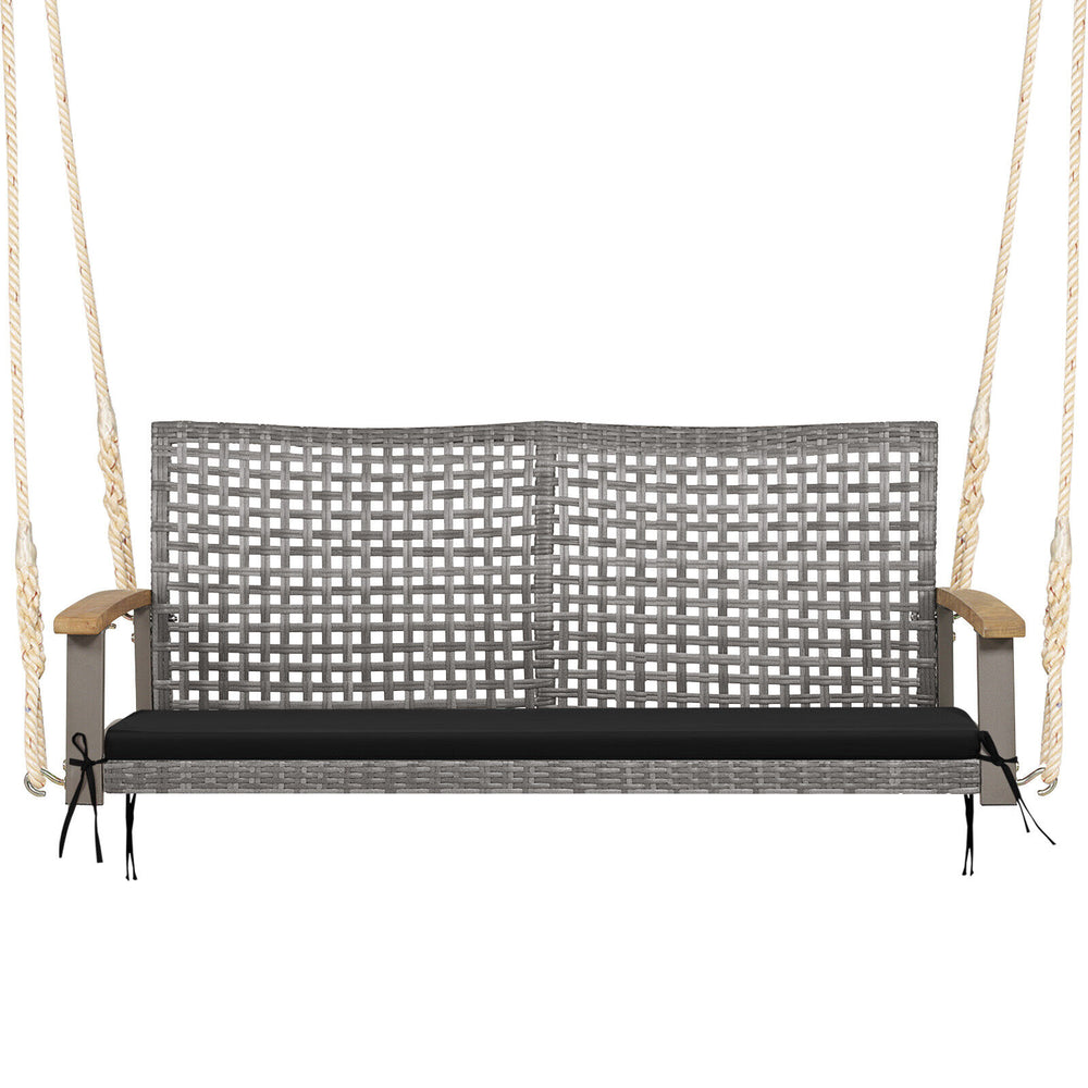 Spacious 2-person patio wicker hanging swing chair with black cushion and acacia wood armrests for outdoor relaxation.