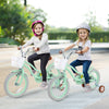 Two kids riding 14-inch mint green bikes with adjustable seats, removable baskets, and training wheels for safety.