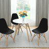 Black Mid-Century Modern DSW dining side chairs with wood legs, elegantly arranged around a white table in a bright.