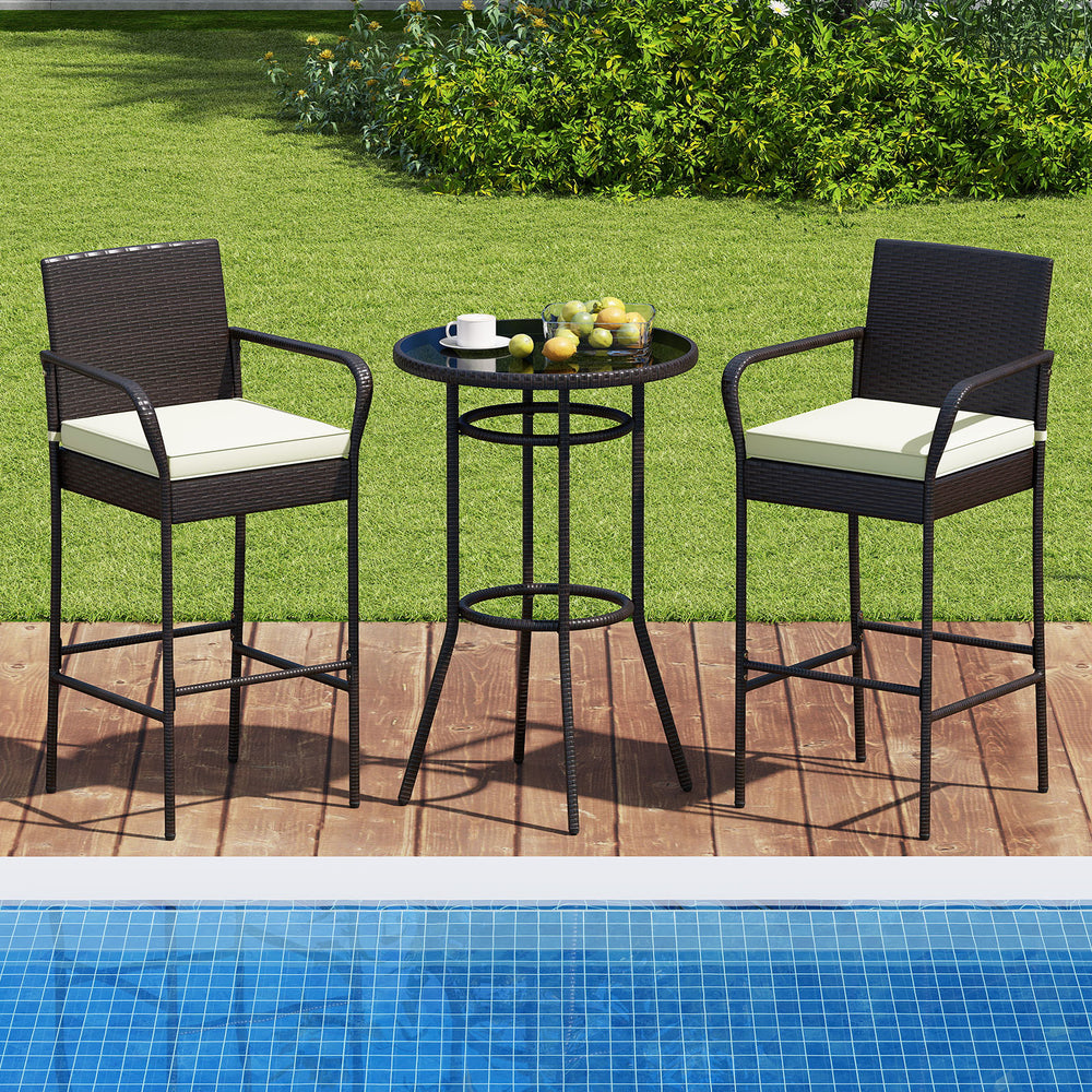 Bar height table and two chairs with white cushions, made of PE wicker, perfect for poolside relaxation.