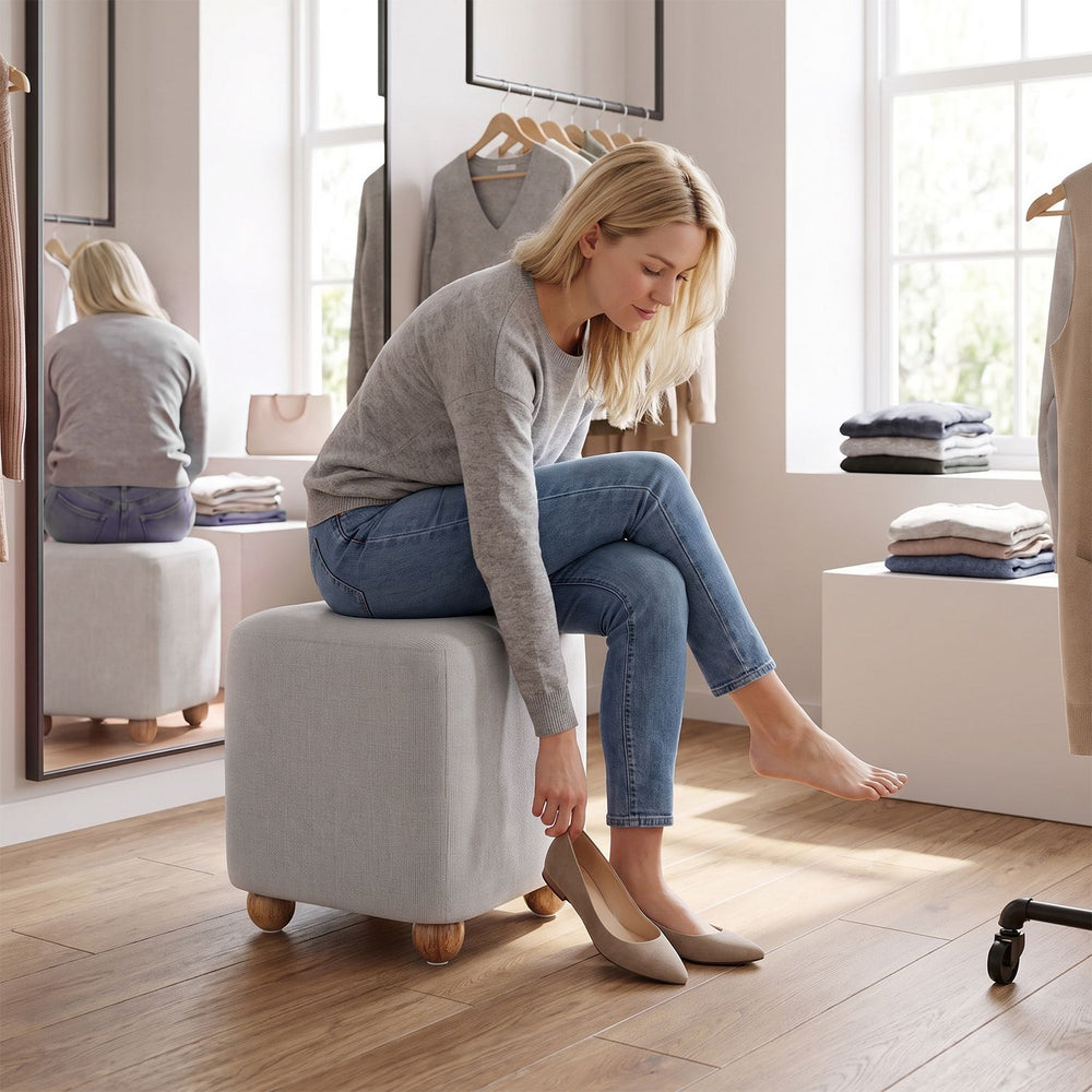 Square gray storage ottoman with rubber wood legs, featuring a cushioned top for seating and hidden storage.