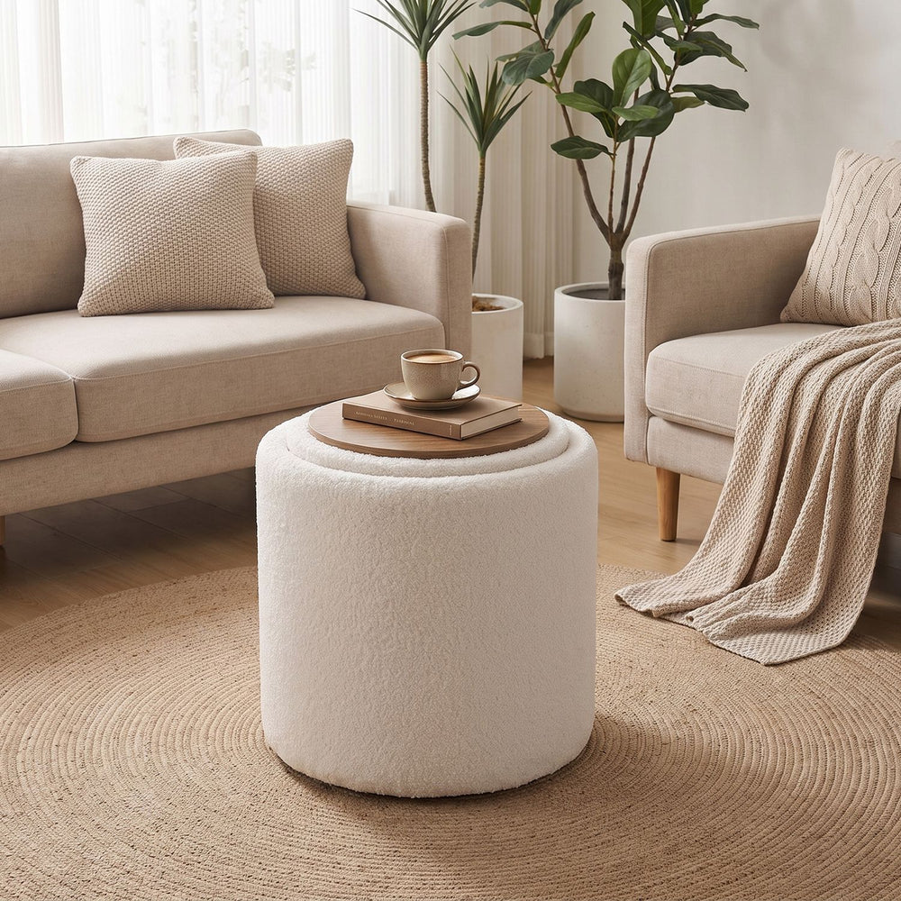 Round beige storage ottoman with a reversible lid, flat wood top, and soft Sherpa fabric for versatile use in any room.