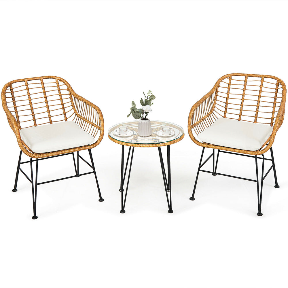 Cushioned rattan chair set with round glass table, perfect for outdoor patio relaxation and entertaining.