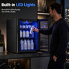 Black 1.55 cu.ft beverage refrigerator with glass door and blue LED lights, shown open while a man grabs a can.