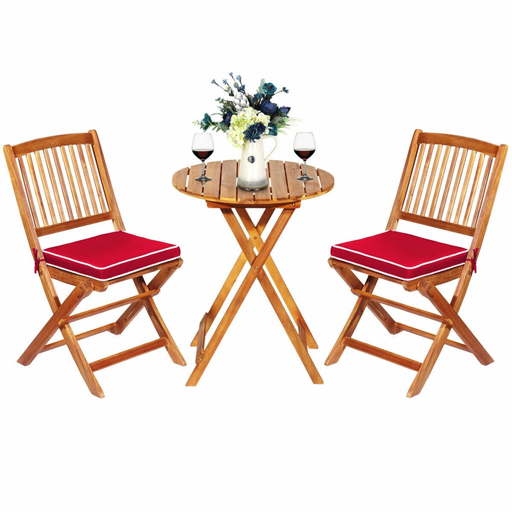 Folding bistro set featuring two acacia wood chairs with red cushions and a round coffee table, perfect for outdoor use.