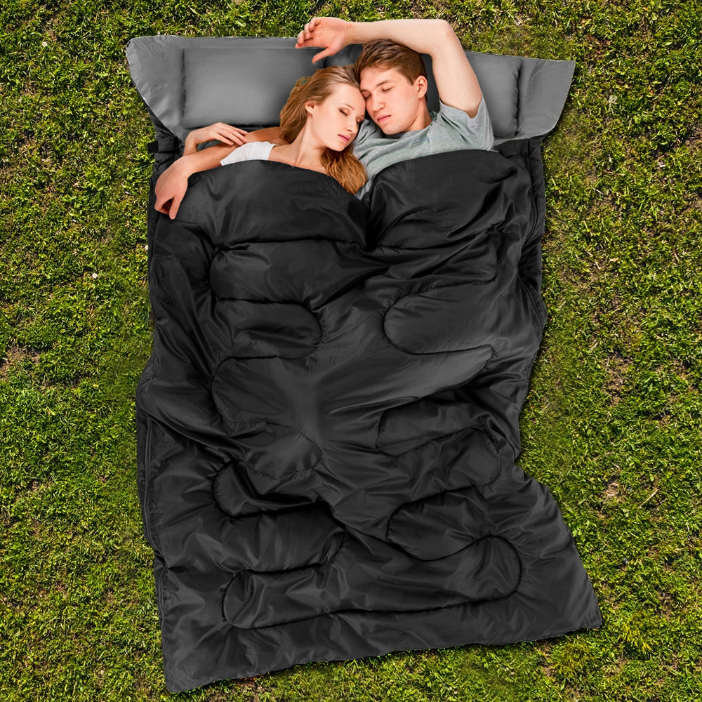 Two-person waterproof sleeping bag in black with two pillows, ideal for camping and outdoor use.