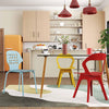 Colorful mid-century dining chairs in blue and red around a glass dining table in a modern kitchen setting.