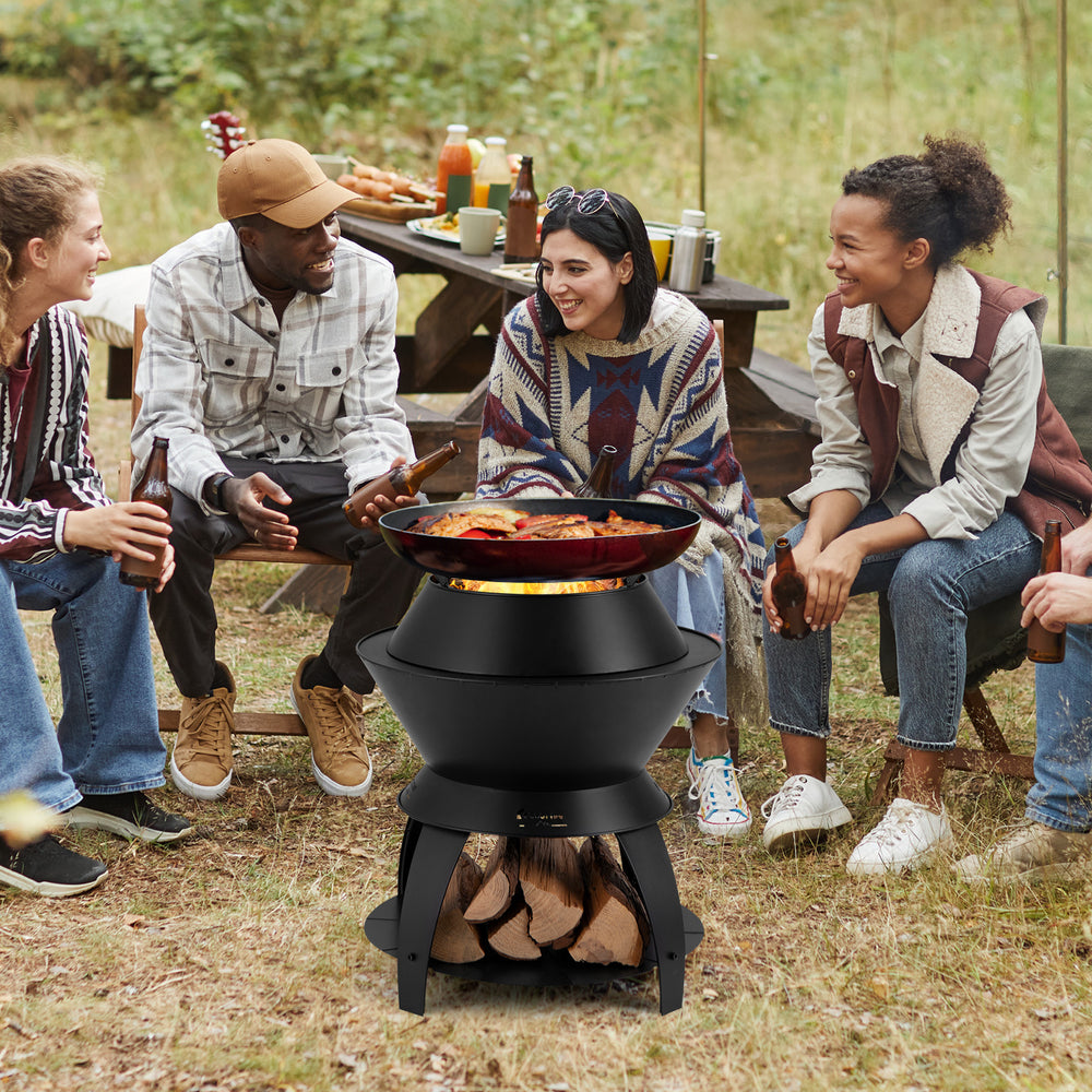 20-inch black patio fire pit with pot holder, surrounded by friends enjoying food and drinks outdoors.