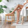 Teak wood shower bench with storage shelf, curved seat design, ideal for shaving legs and holding shower supplies.