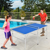Portable 60-inch blue ping pong table with paddles and balls, set up for play by the poolside.