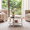 Round 2-tier coffee table with solid wood legs, featuring a white finish and open storage shelf for a tidy living area.