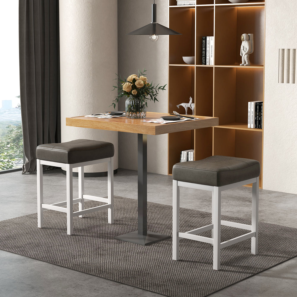 Set of 2 black and white saddle stools with cushioned seats, perfect for counter height tables and bars.