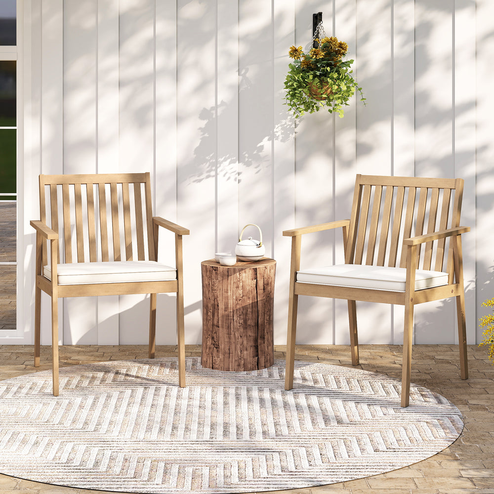 Two acacia wood patio dining chairs with removable cushions, placed on a rug for outdoor relaxation.