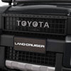 Close-up of the Toyota Land Cruiser front grille on a black 24V kids' ride-on car with remote control features.