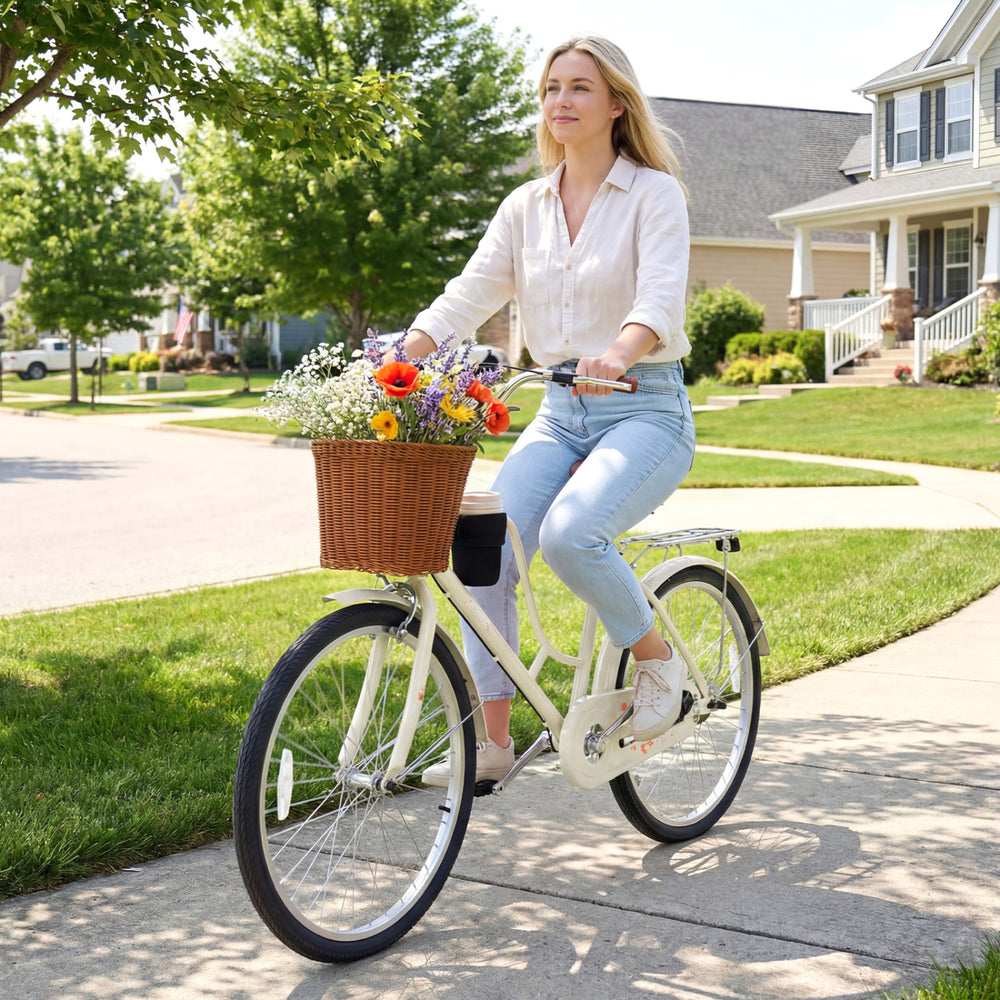 A woman rides a beige 24-inch beach cruiser bike with a woven basket and cup holder, perfect for leisurely outings.