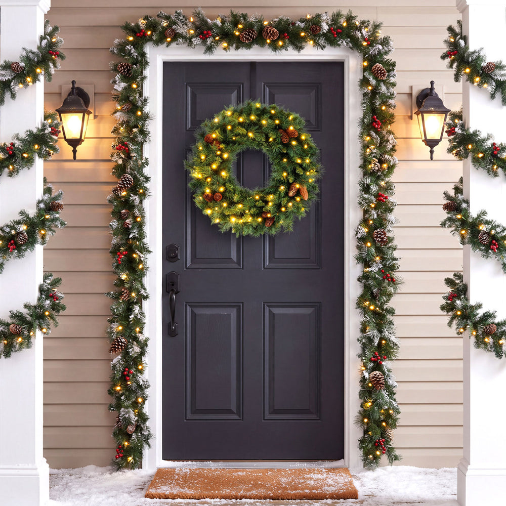 The 24" pre-lit Christmas wreath features 50 warm white LED lights and natural pine cones for festive door decor.