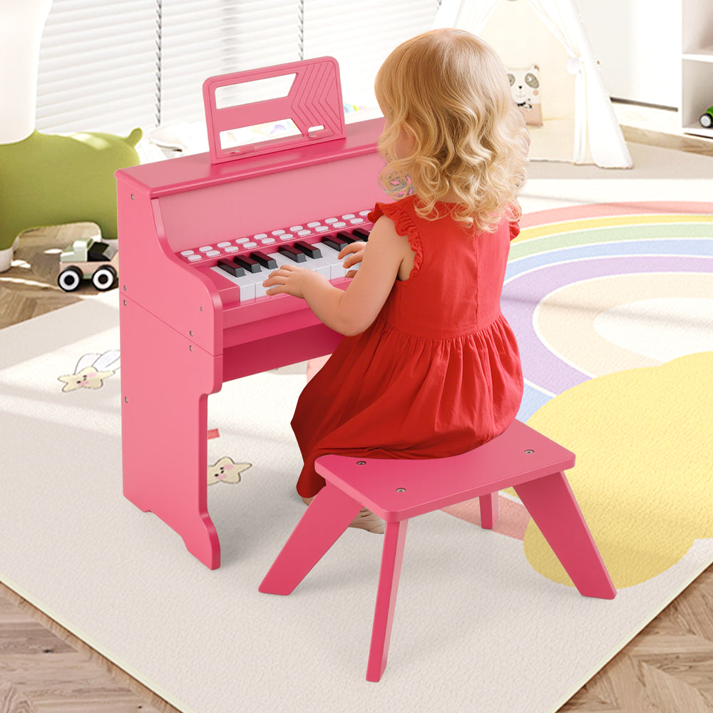 Kids playing on a pink 25-key piano with a matching stool, perfect for toddlers' musical exploration.