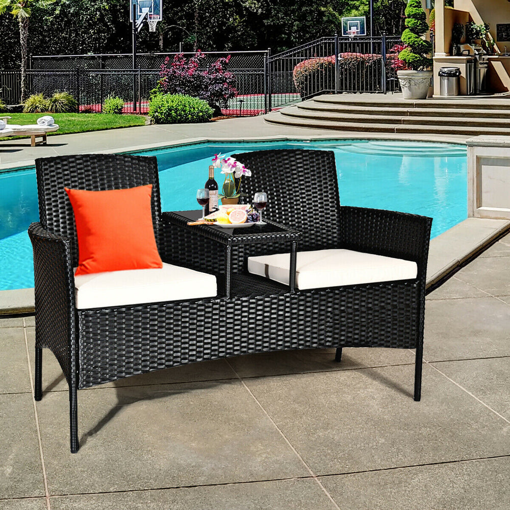 Wicker patio conversation set with removable cushions, featuring a tempered glass table, ideal for poolside relaxation.