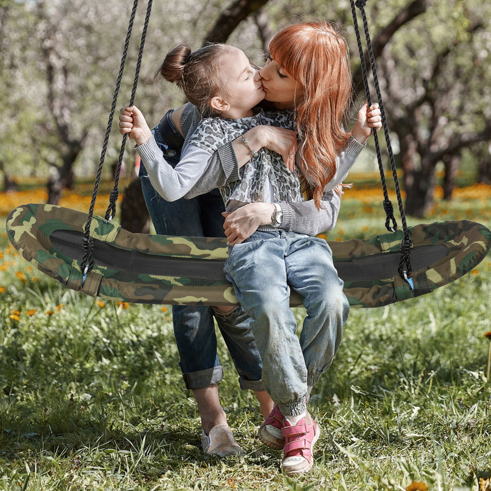 Kids enjoying the Saucer Tree Swing, featuring a durable metal frame and comfortable foam padding, perfect for outdoor.
