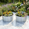 Galvanized raised garden bed kit with vibrant flowers, featuring a round open-ended base for drainage and airflow.