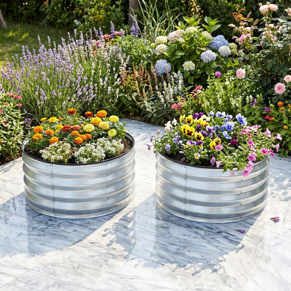 Galvanized raised garden bed kit with vibrant flowers, featuring a round open-ended base for drainage and airflow.