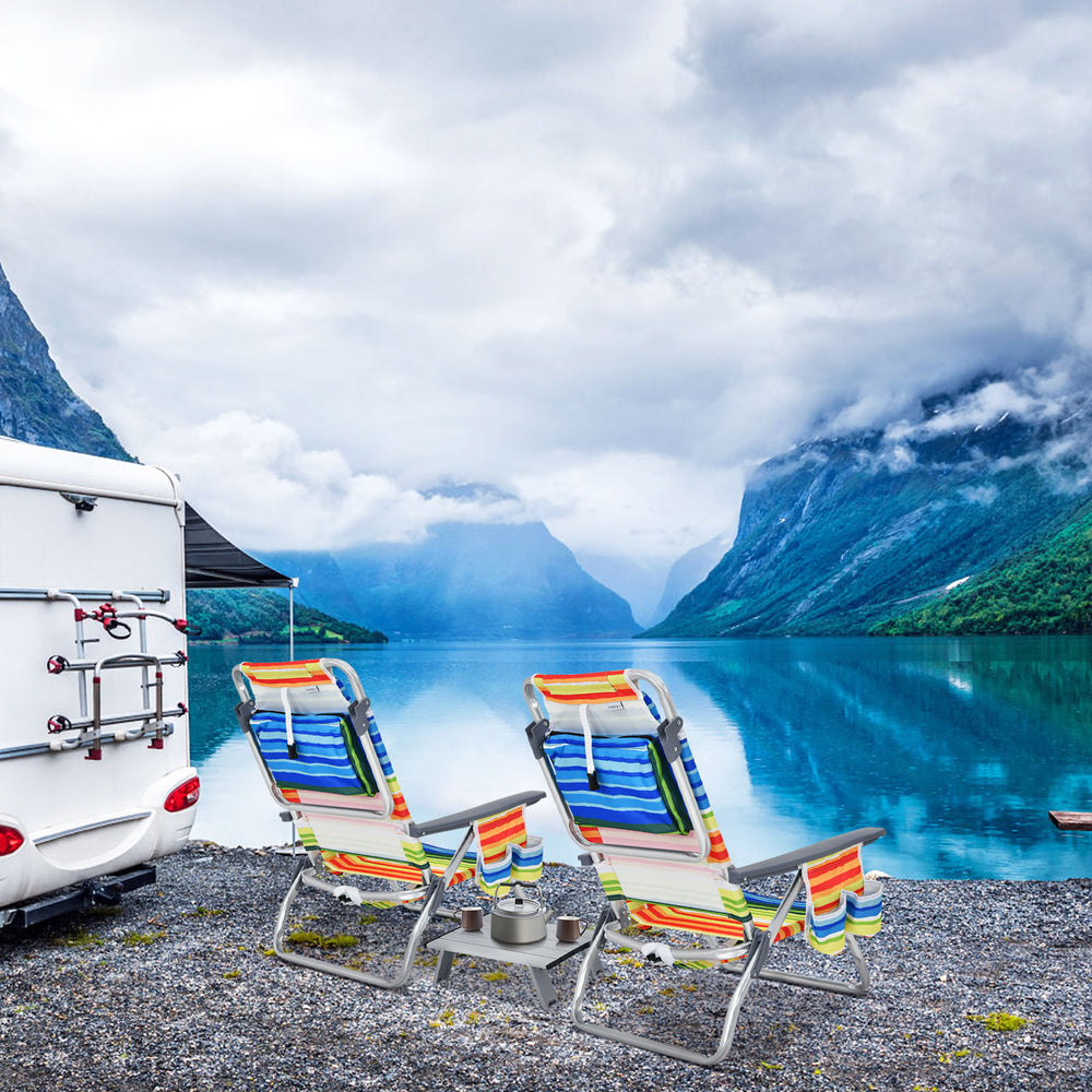 Two colorful folding beach chairs with a side table by a lake, perfect for outdoor relaxation and leisure activities.