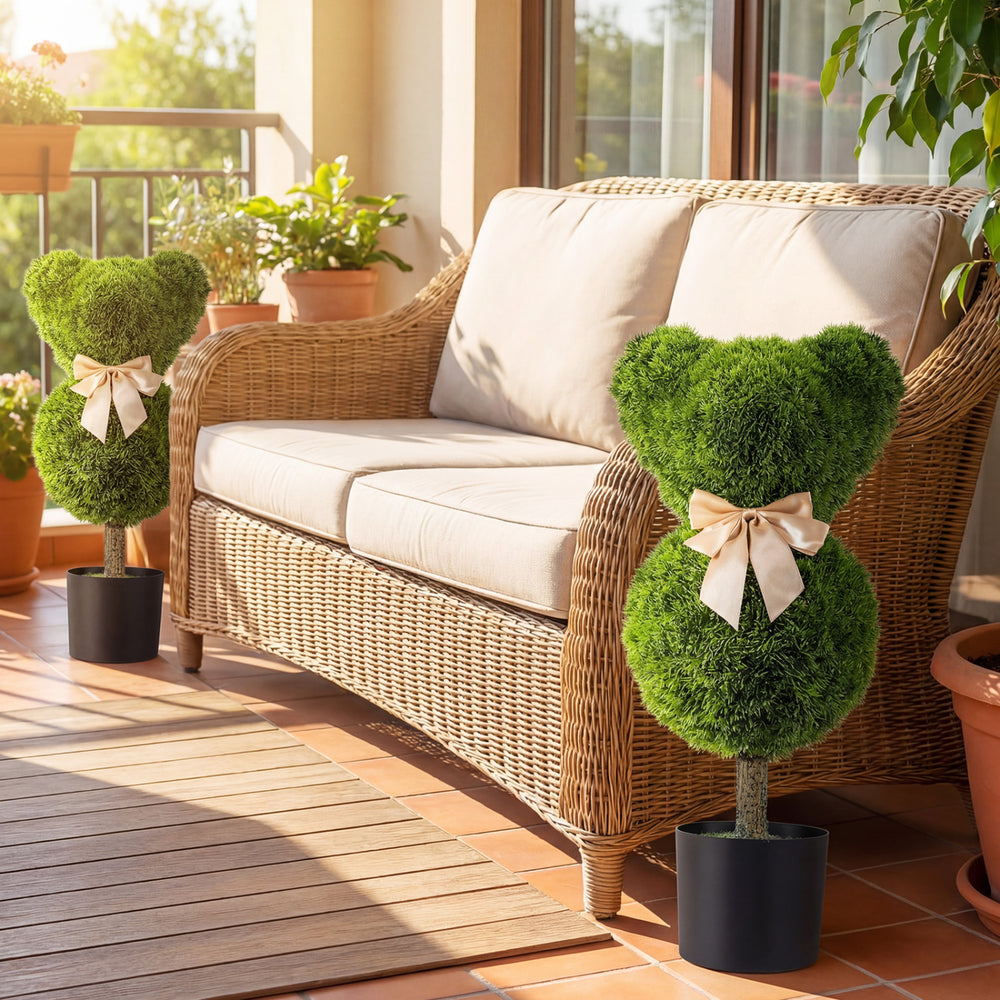 Two bear-shaped topiary trees with golden bows in cement-filled pots, perfect for playful outdoor decoration.
