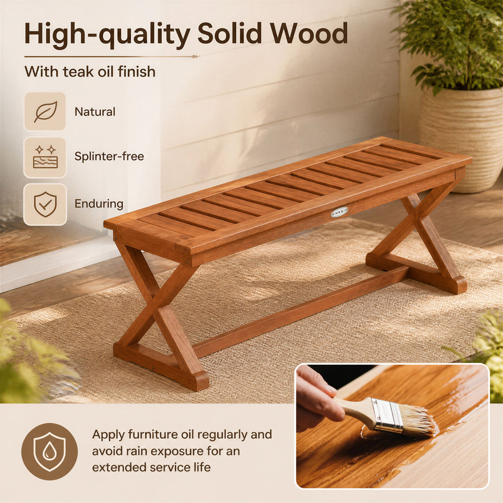 Outdoor bench made of solid hardwood with a teak finish, featuring a slatted seat and cross legs for patio use.
