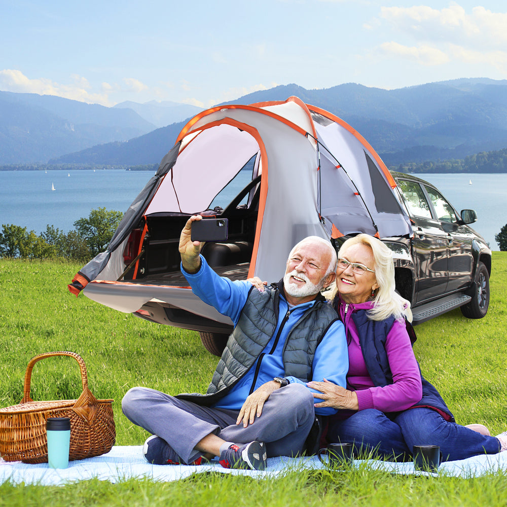 Portable pickup tent for 2-3 people with detachable cover, set up near a lake for outdoor adventures.
