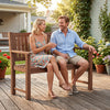 Two people relax on a brown 2-seater outdoor wooden bench with backrest and armrests in a vibrant garden setting.