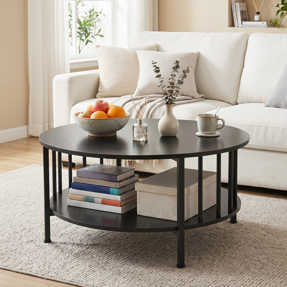 Round 2-tier coffee table in black walnut with metal accents, featuring a storage shelf for books and decor in a living.