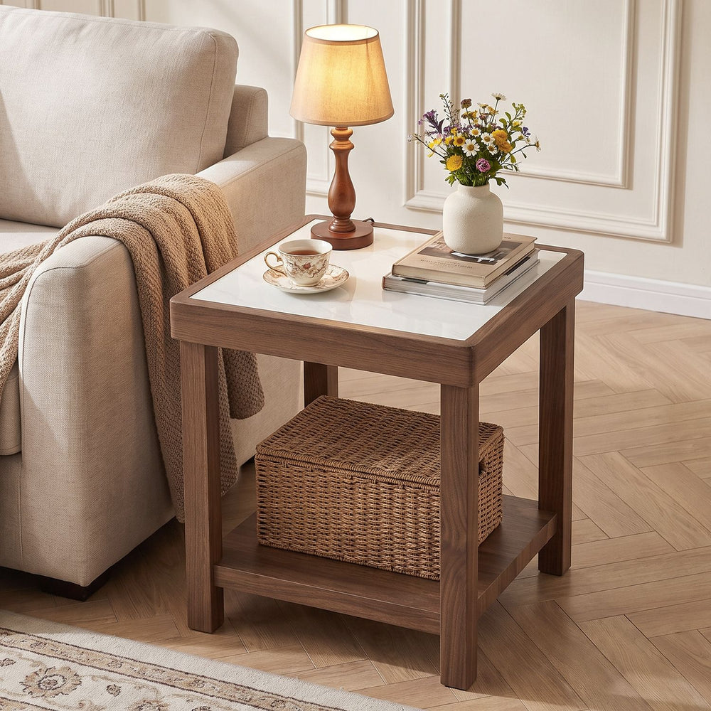 Two-tier square side table with faux marble tempered glass top and walnut rubberwood legs, shown beside a living room sofa.