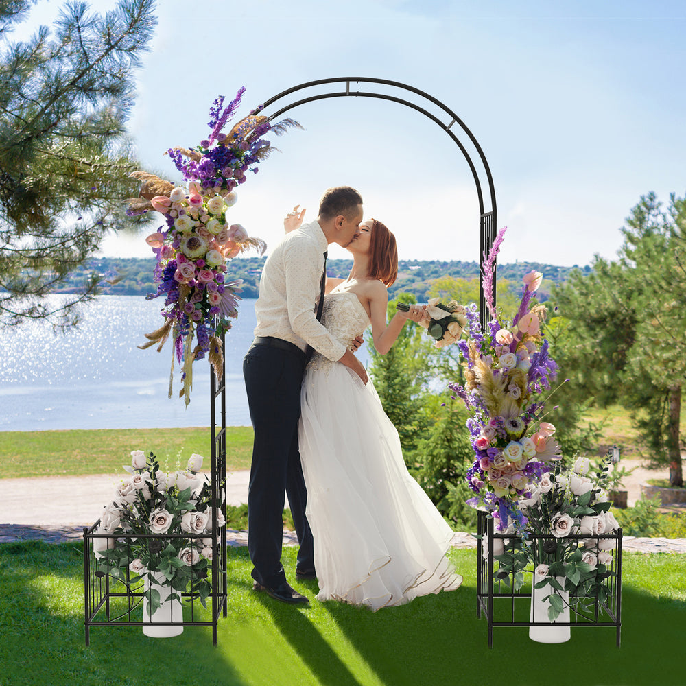 Garden arbor with side planters, decorated for a wedding, featuring a stylish arc top and sturdy black metal frame.
