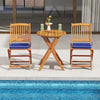 Two outdoor folding chairs with navy seat cushions and a wooden table, perfect for poolside dining or relaxation.