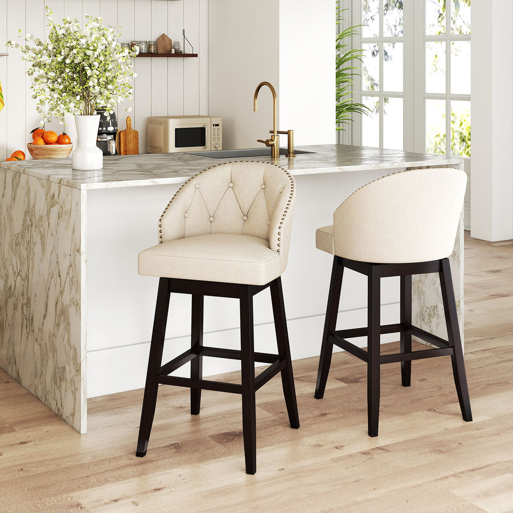 Beige padded bar stool with rubber wood frame and swivel seat, featuring tufted buttons, ideal for kitchen islands.