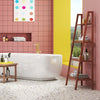 Teak utility bench and bamboo ladder shelf in a modern bathroom, ideal for laundry supplies and decorative items.