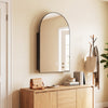 Arched mirror with brushed metal frame above a storage cabinet featuring adjustable shelves for versatile organization.