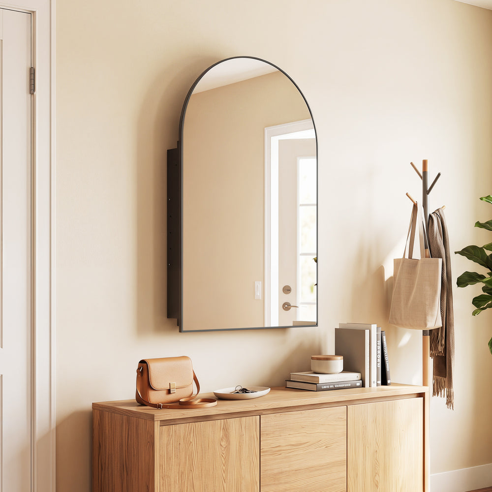 Arched mirror with brushed metal frame above a storage cabinet featuring adjustable shelves for versatile organization.