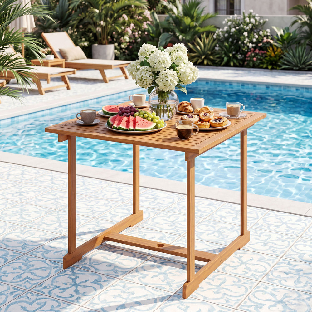 Acacia wood outdoor dining table with umbrella hole, set for four, ideal for poolside meals and gatherings.