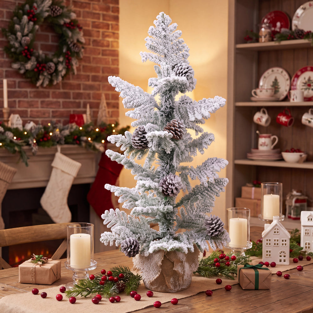 Mini tabletop Christmas tree with snow-flocked PE leaves, featuring pine cones and a stable linen-wrapped base for festive decor.